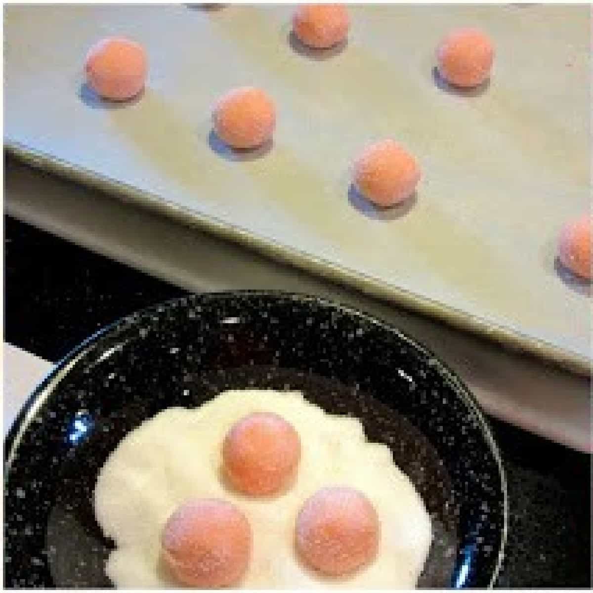 Balls of pink cookie dough dipped into sugar.