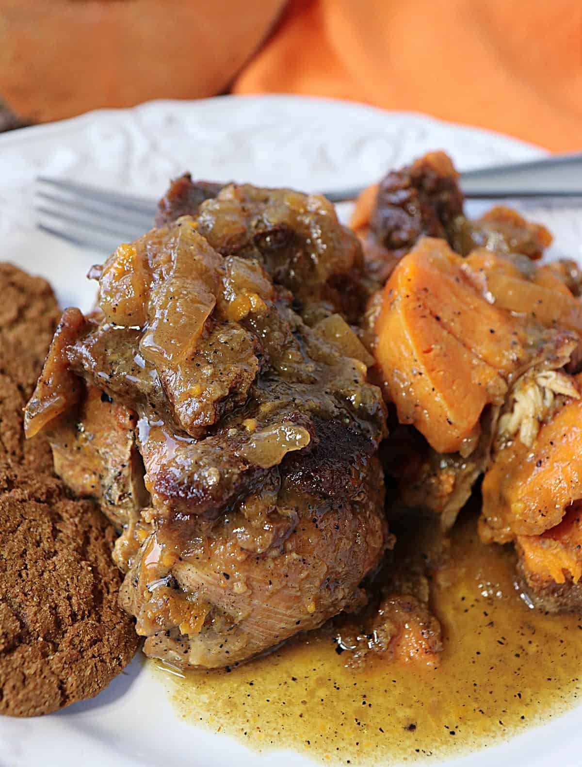 Worried that your chicken breasts are always dry and boring? No longer. These fork-tender Apple Cider Braised Chicken Breasts with Sweet Potatoes and Gingersnaps are anything but dry and boring! - kudoskitchenbyrenee.com Juicy, brown chicken breast on a white plate with sweet potatoes and gingersnaps.