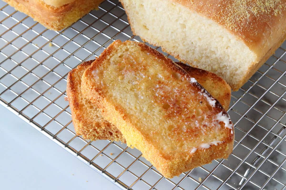 A wire rack with two baked loaves of homemade English muffin bread.