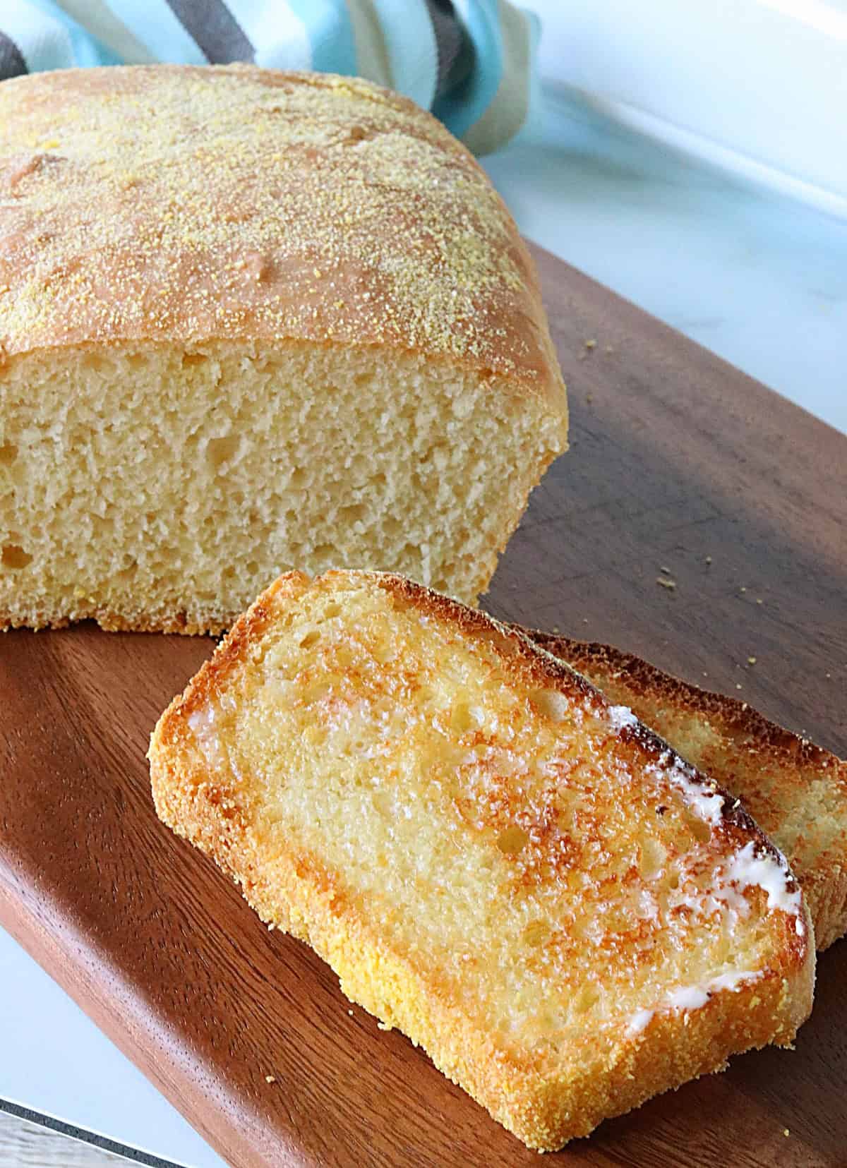Two slices of toasted English muffin bread with the remainder of the loaf in the background.