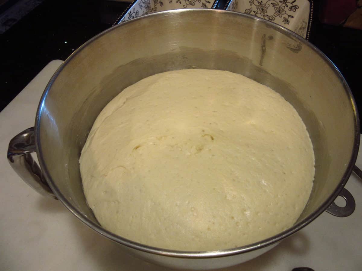 A fully risen English muffin bread dough in a stand mixer bowl.