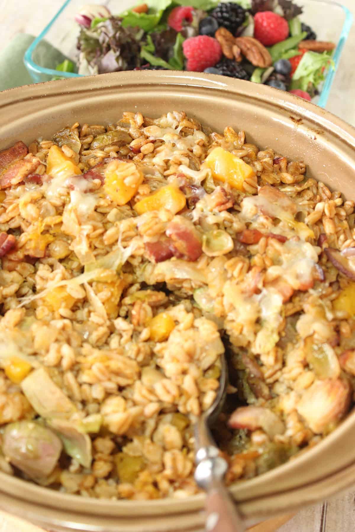 A brown casserole dish filled with farro casserole with Brussels sprouts and bacon.