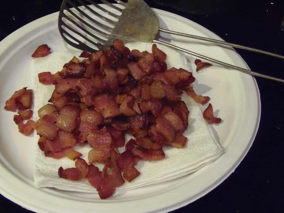 Cooked bacon on a paper plate with napkins to soak up the grease.
