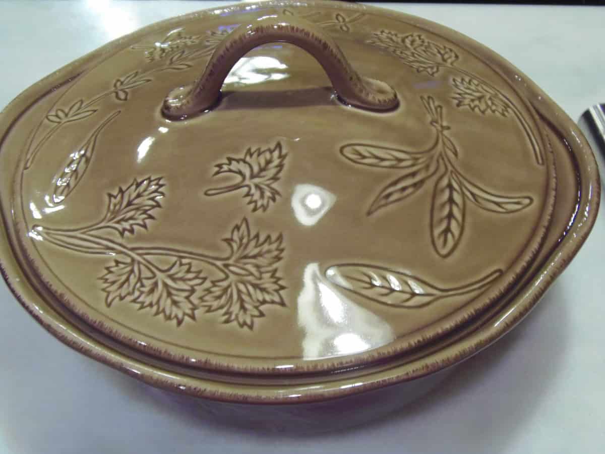 A round, covered, tan casserole dish on a countertop.