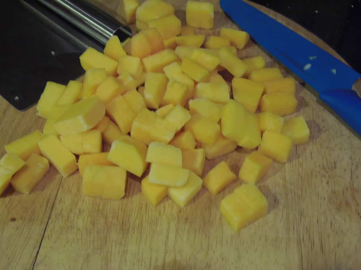 Butternut squash chunks on a wooden cutting board.