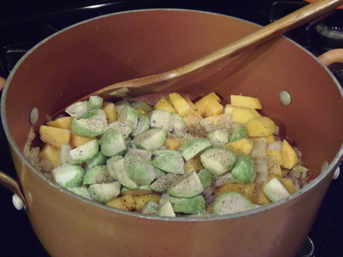 Trimmed raw Brussels sprouts and butternut squash cubes in a stockpot.