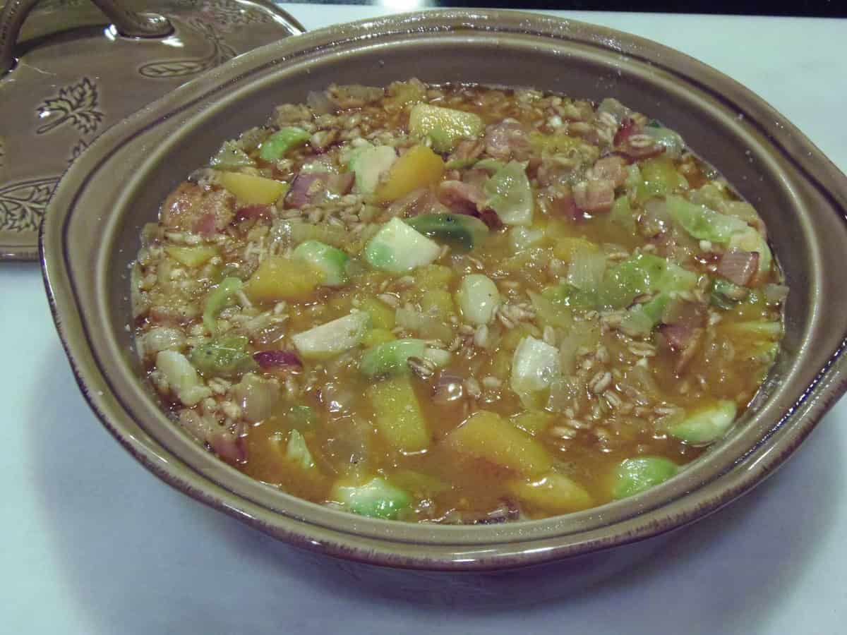 A farro casserole before baking in a tan, round casserole dish.