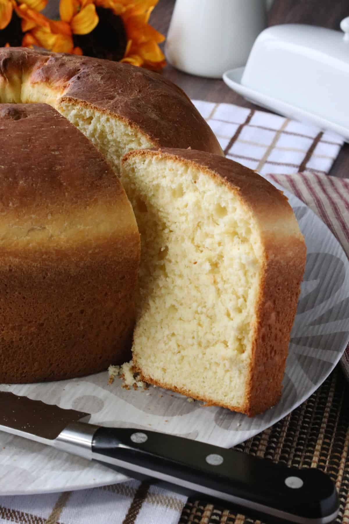 A Perfectly baked round loaf of Sally Lunn bread with a slice taken out to show texture.