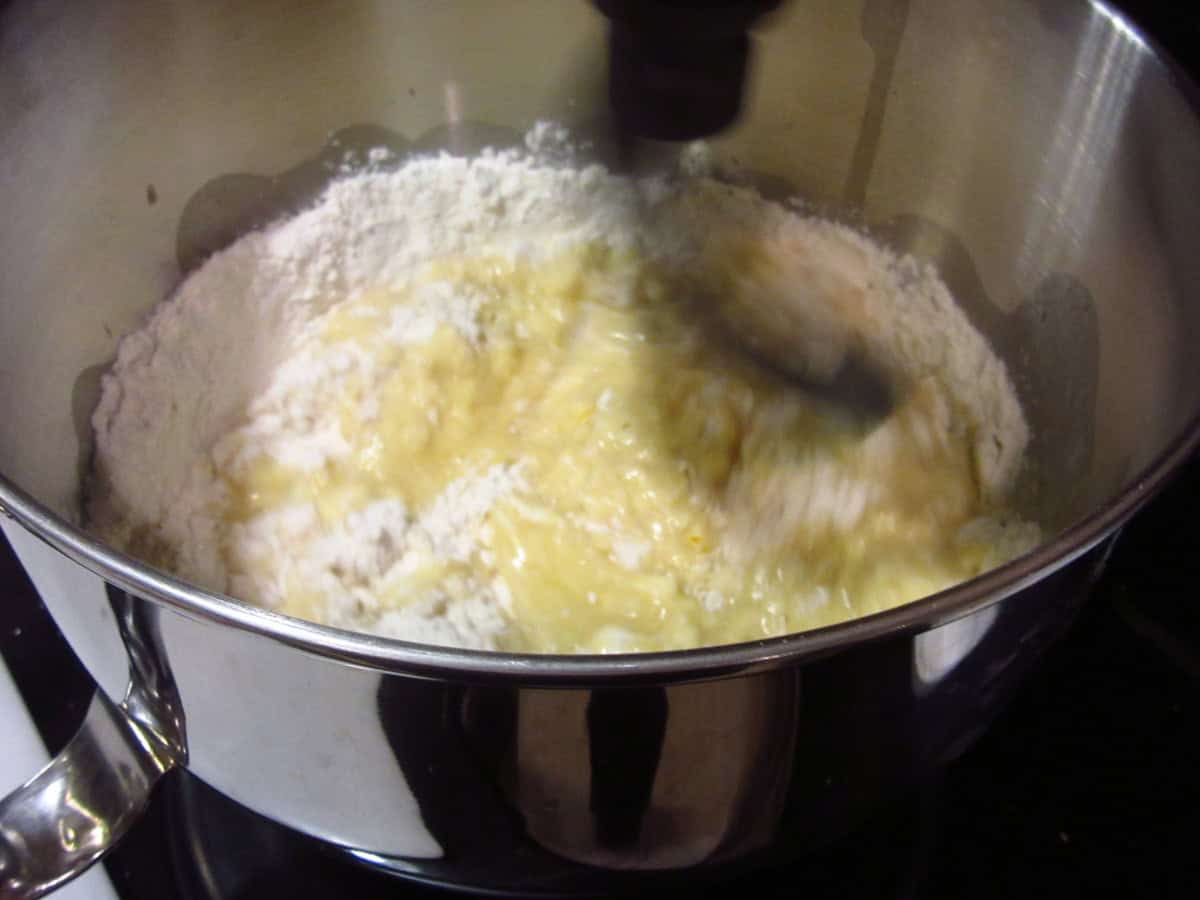 A bread dough being mixed in a stand mixer with the dough hook.