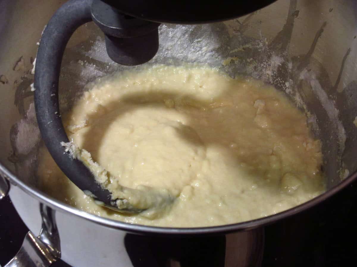 A wet and sticky bread dough beginning in a stand mixer bowl.