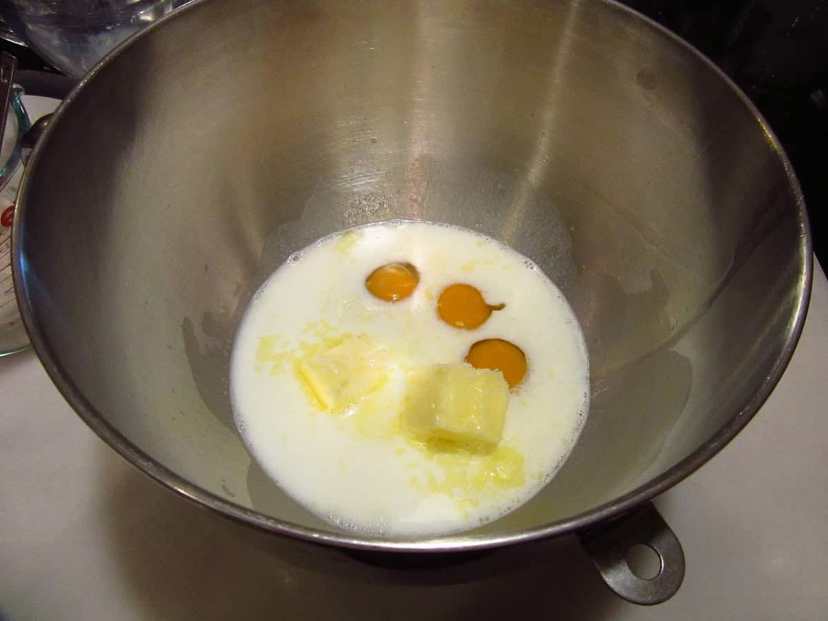 Milk, softened butter and three eggs in a bowl of a stand mixer.