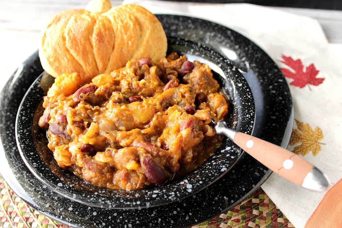 A black bowl with a large serving of slow cooker butternut squash chili with beans and sausage.