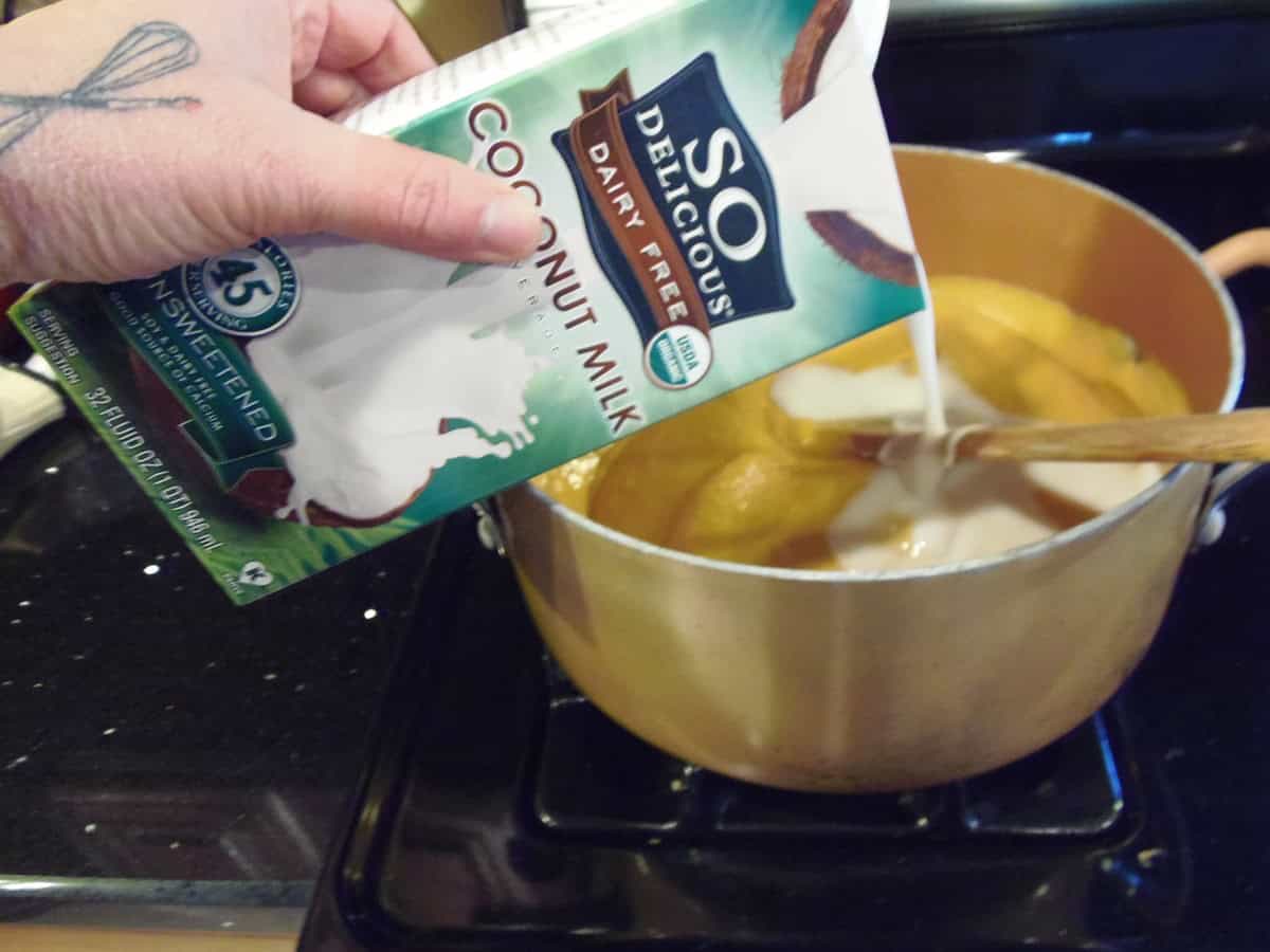 Coconut milk being added to a sweet potato chowder on the stovetop.