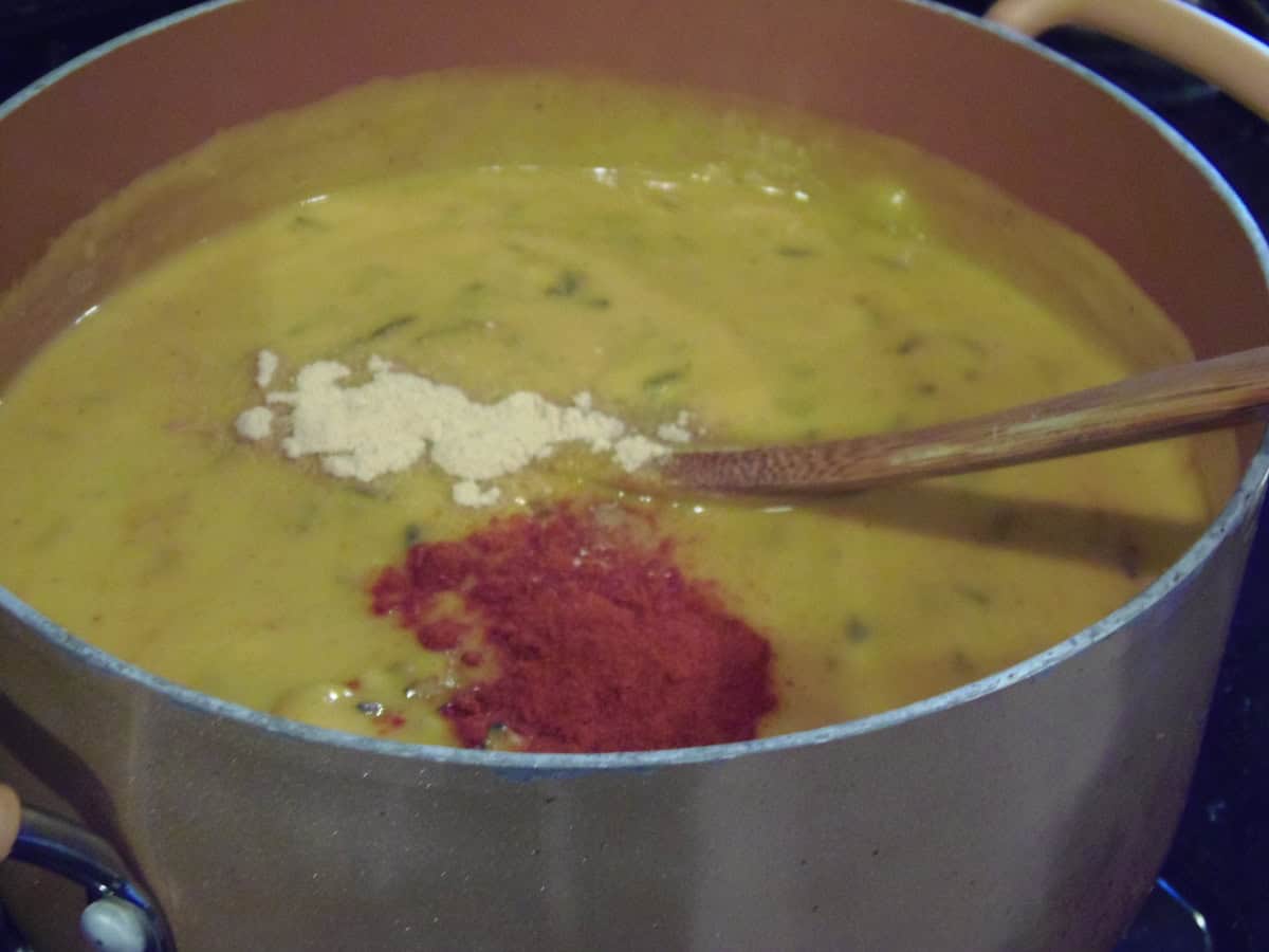 Spices in a soup pot of sweet potato chowder with wild rice.
