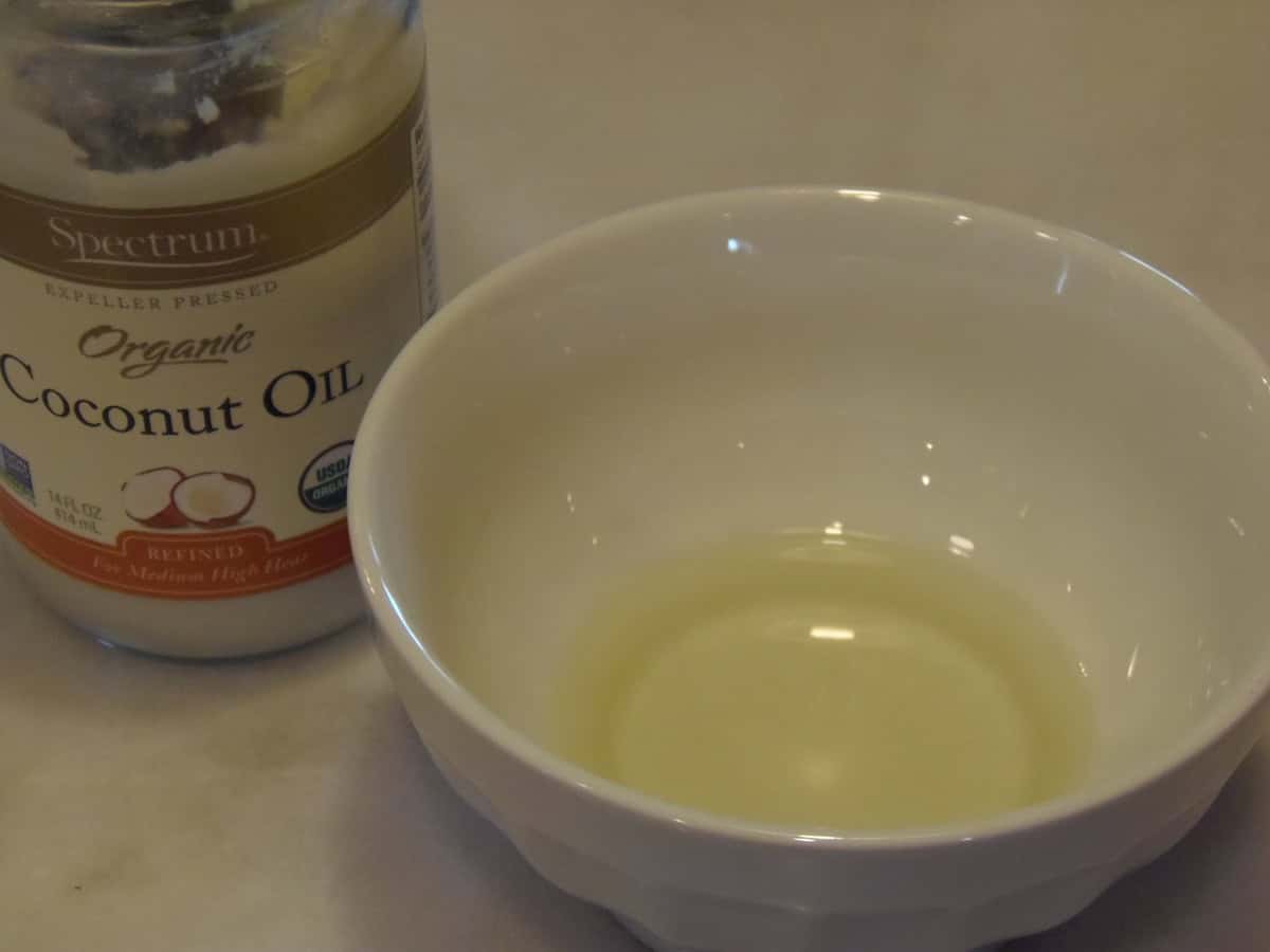 Melted coconut oil in a small white bowl.