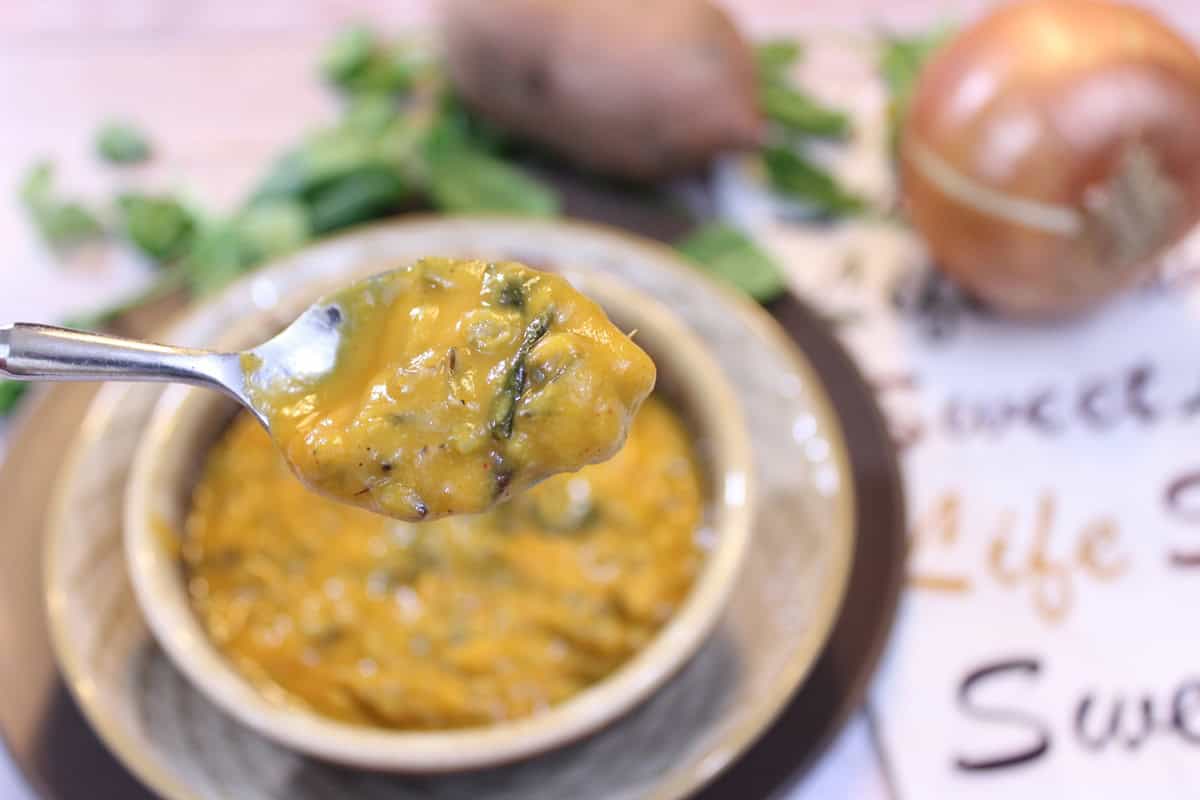 Roasted Sweet Potato and Wild Rice Chowder A close up of a spoon holding a bite of sweet potato soup.