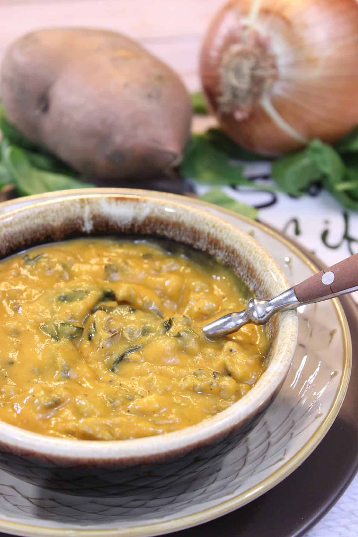 Roasted Sweet Potato and Wild Rice Chowder A rustic brown bowl with a serving of sweet potato chowder with wild rice.