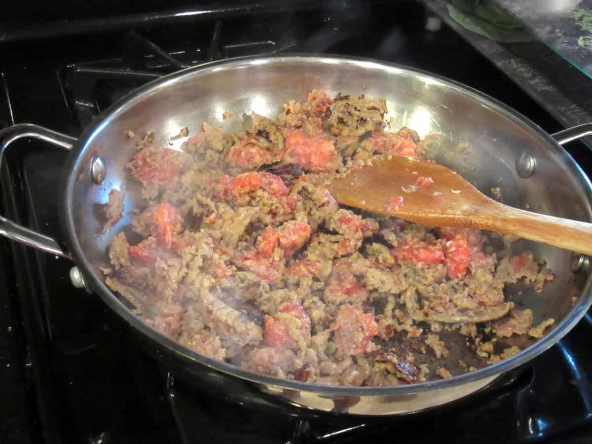 Browning Italian sausage in a large sauté pan on the stovetop.