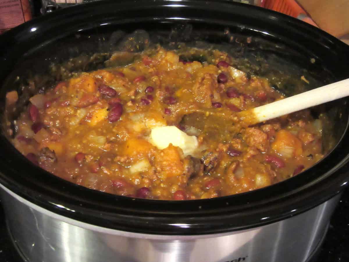 A tablespoon of melting butter in a slow cooker with butternut squash chili.