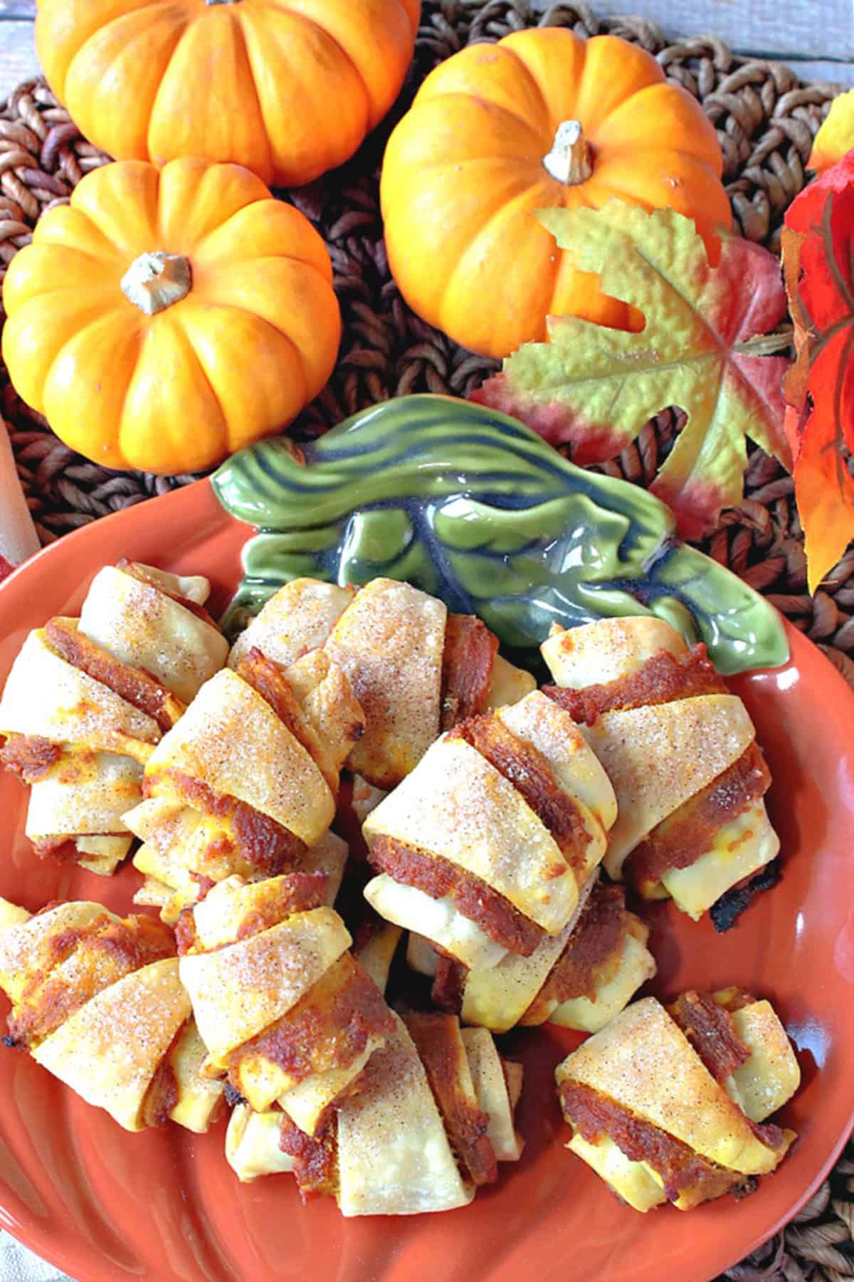 A cute orange pumpkin plate stacked with crescent shaped pumpkin pie bites.