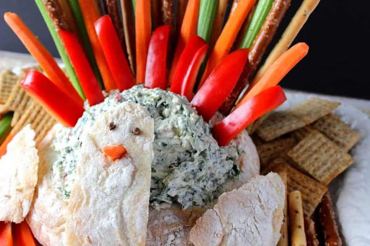 Spinach dip piled high in a bread bowl turkey for Thanksgiving.